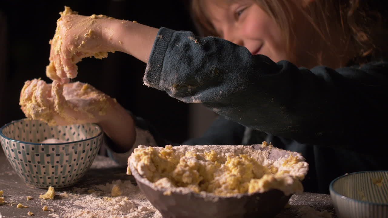 Happy little girl playing with sugar with messy hands full of butter while baking