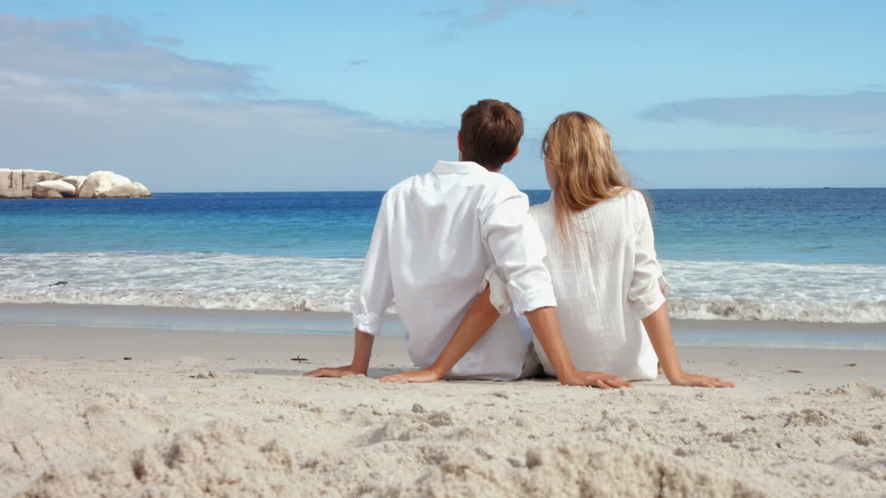 Coppia felice seduto sulla spiaggia