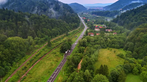 Scenic road in green hills. A highway cuts through lush green valleys and forested hills under cloudy skies, creating a tranquil landscape