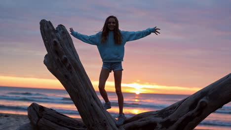 young girl enjoying sunset on driftwood at the beach