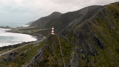 people going down on steep steps on cliff from cape palliser lighthouse in new zealand