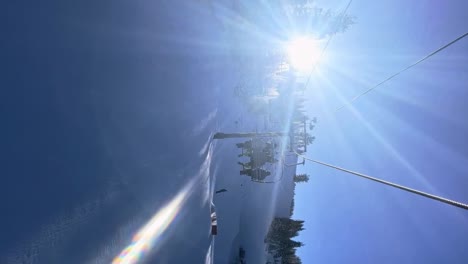 tilt up vertical handheld shot riding on a slow ski lift in the utah wasatch mountains on a bright sunny winter day with a small train park below