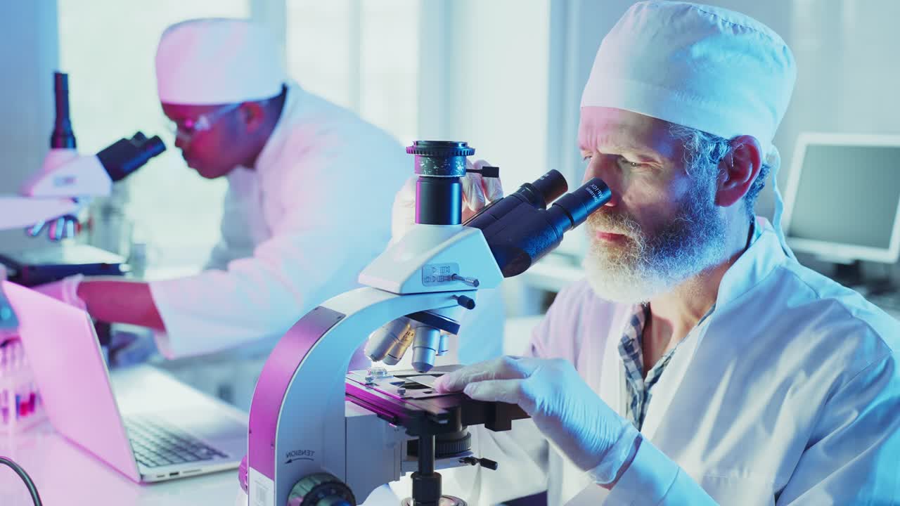 Two Male Scientists Working with Microscopes in a Modern Laboratory