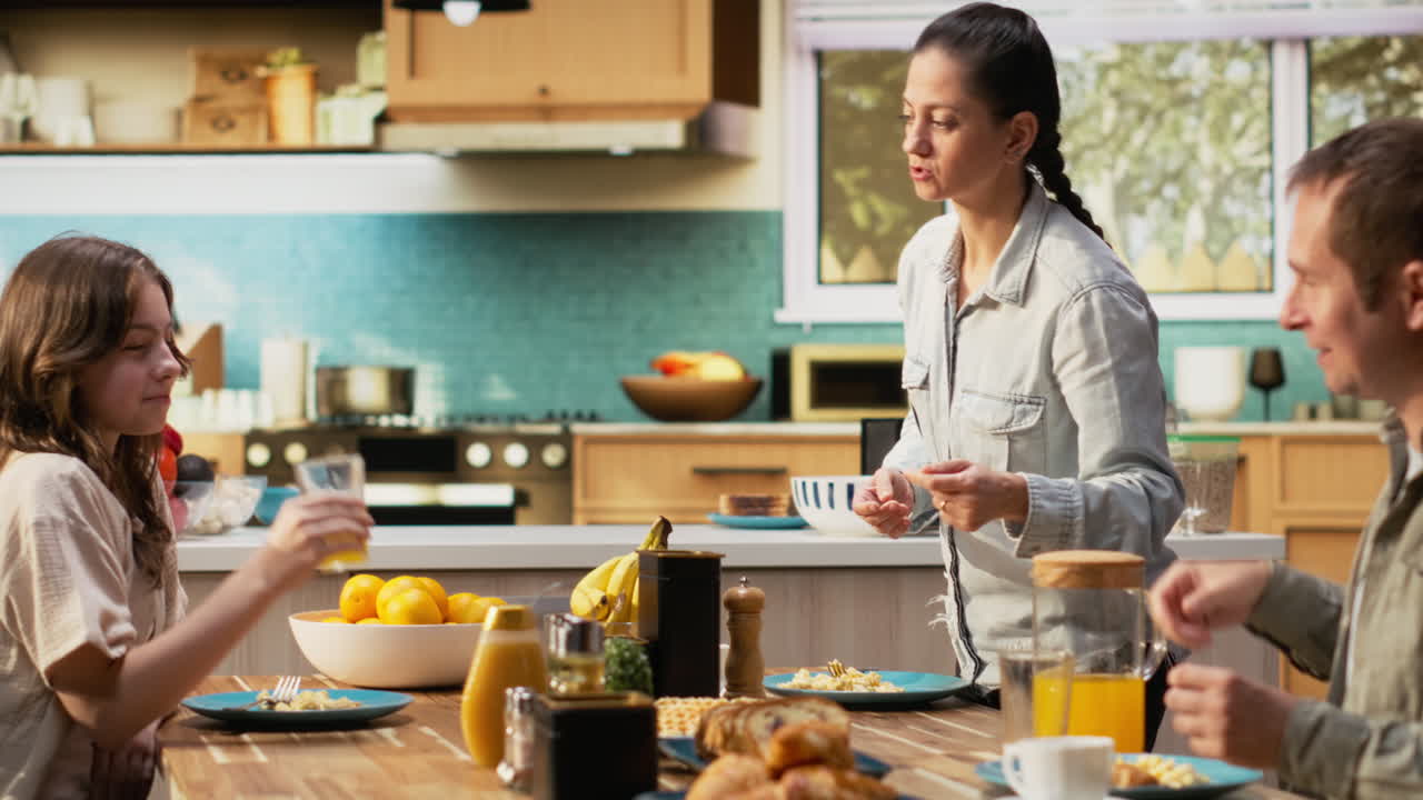 Family with a pre-teen girl serving breakfast together in a bright kitchen