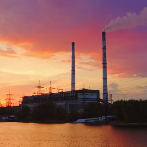 manufacturing near the river. industrial plant and high voltage electric towers among nature at sunset. view from the river. aerial view.