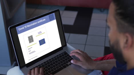 man working at table, covid vaccination certificate with qr code and eu flag on laptop screen