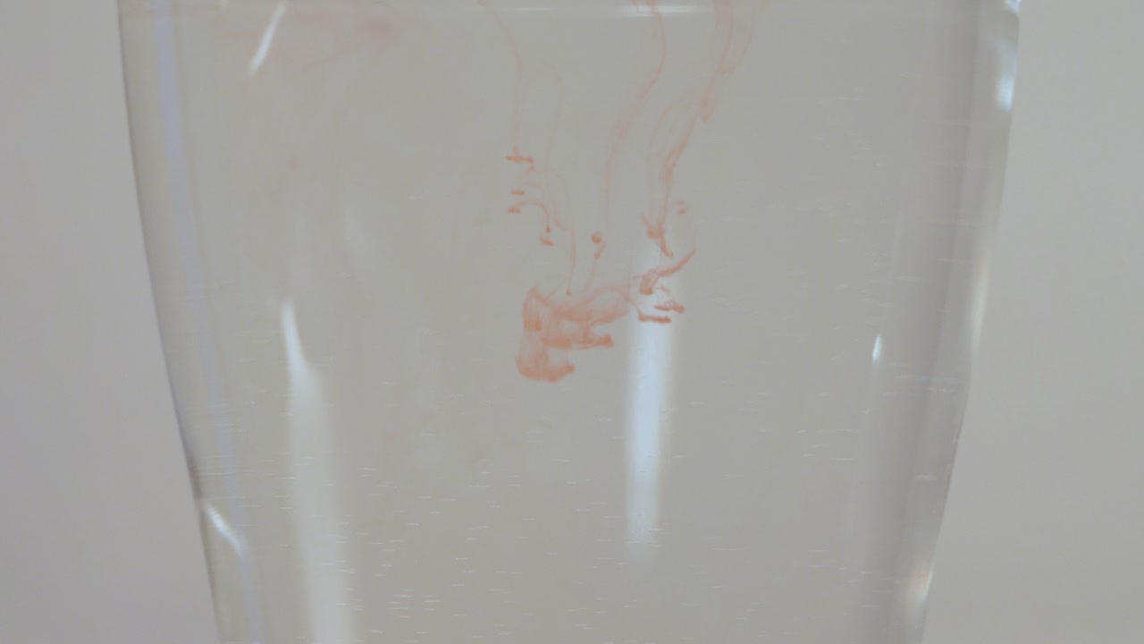 다른 색상의 수채화 점을 물 한 잔에 떨어뜨리기