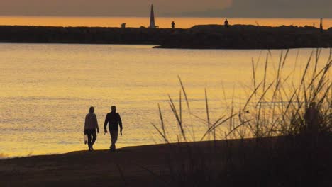 Pareja-Mayor-Caminando-En-La-Playa-Juntos-Al-Amanecer,-Silueta-Contra-El-Mar-En-Calma,-Cámara-Lenta