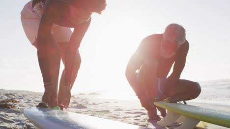 Happy-african-american-couple-preparing-before-surfing-on-sunny-beach