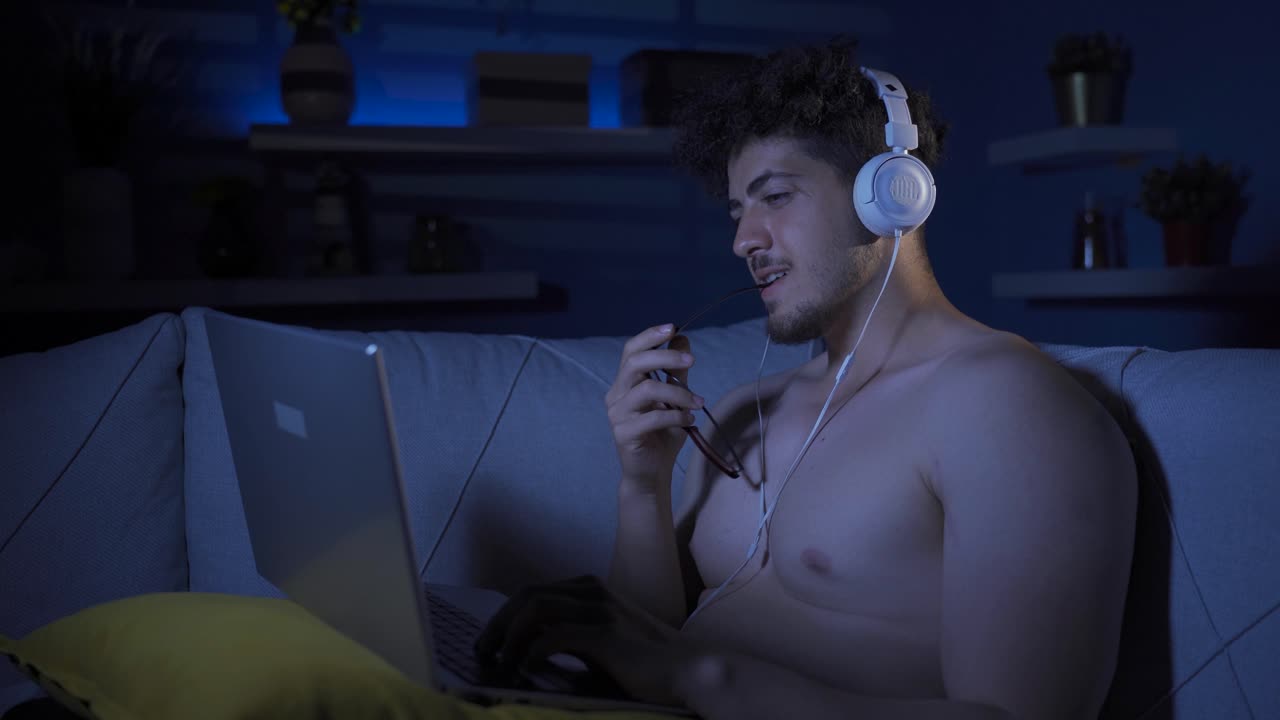 행복하고 쾌활한 젊은이가 노트북을 집중적으로 쳐다보고 있습니다.