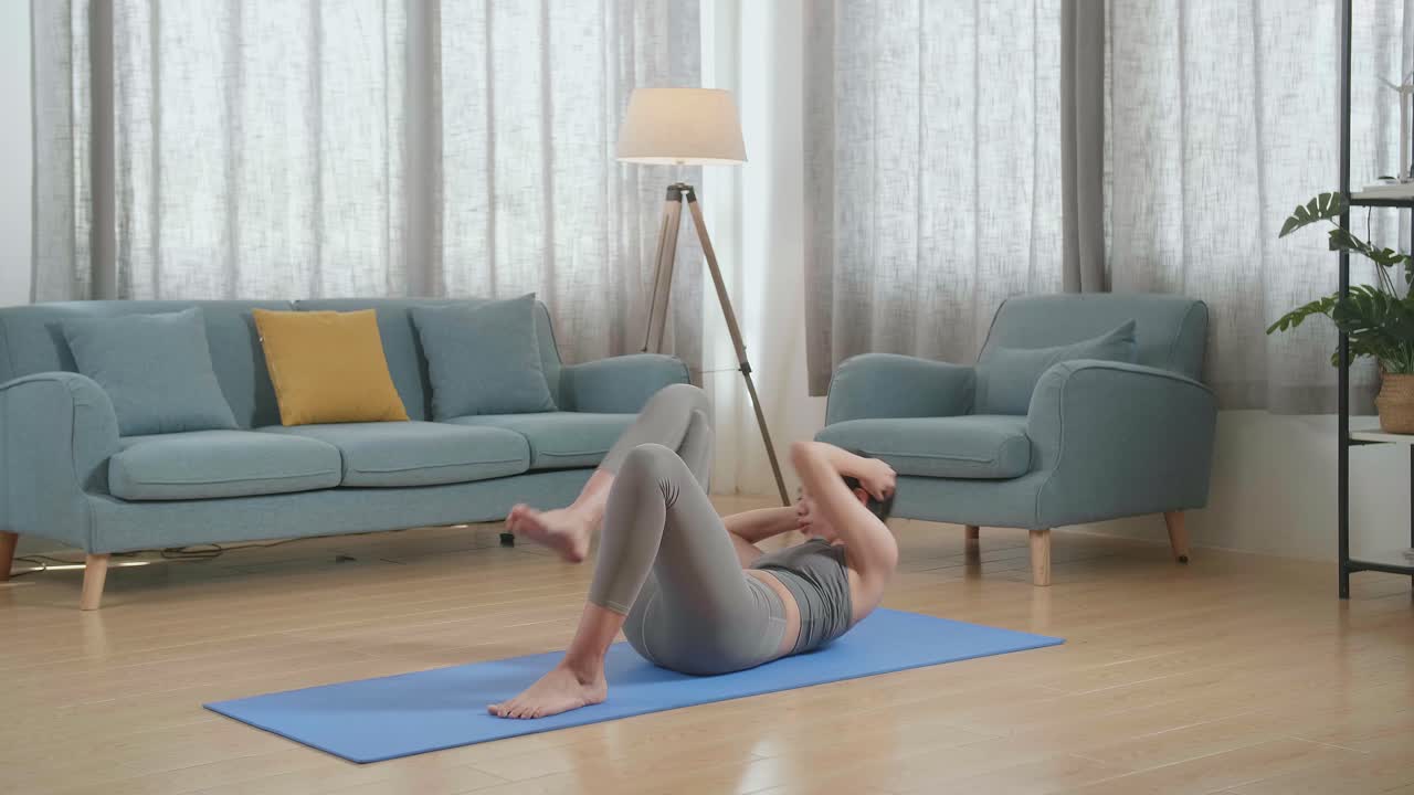joven atleta asiática con ropa deportiva haciendo ejercicios de crisscross crunch mientras entrena en casa