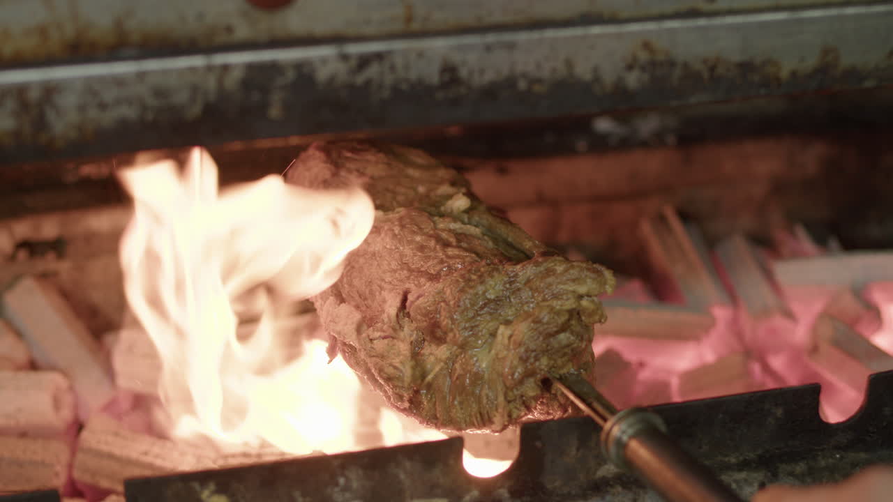 Cook roasts juicy brazilian barbecue kebab on the grill slowmotion