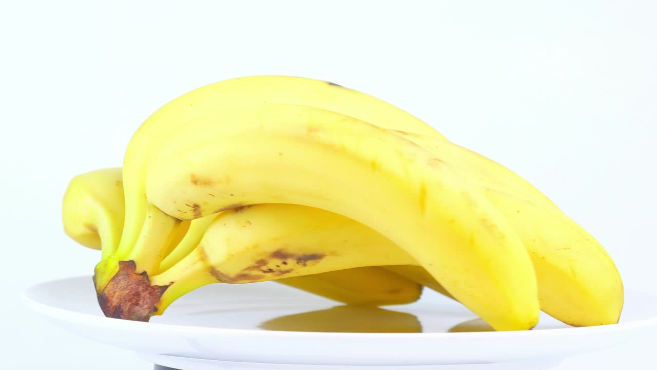 색 바탕에 있는 접시에 바나나. 음식. 과일. 비디오.