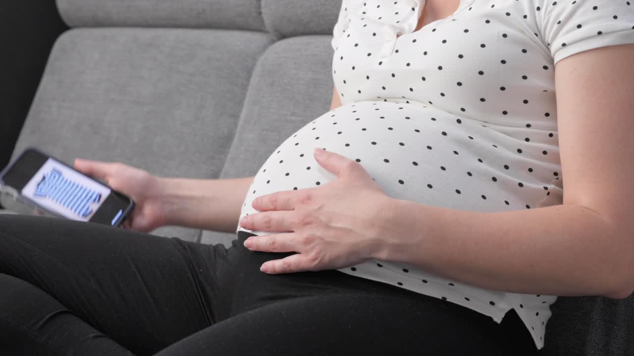 Pregnant woman on sofa using phone