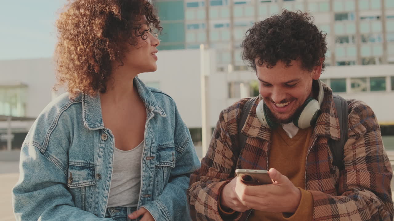 Couple of students using smartphone outdoors