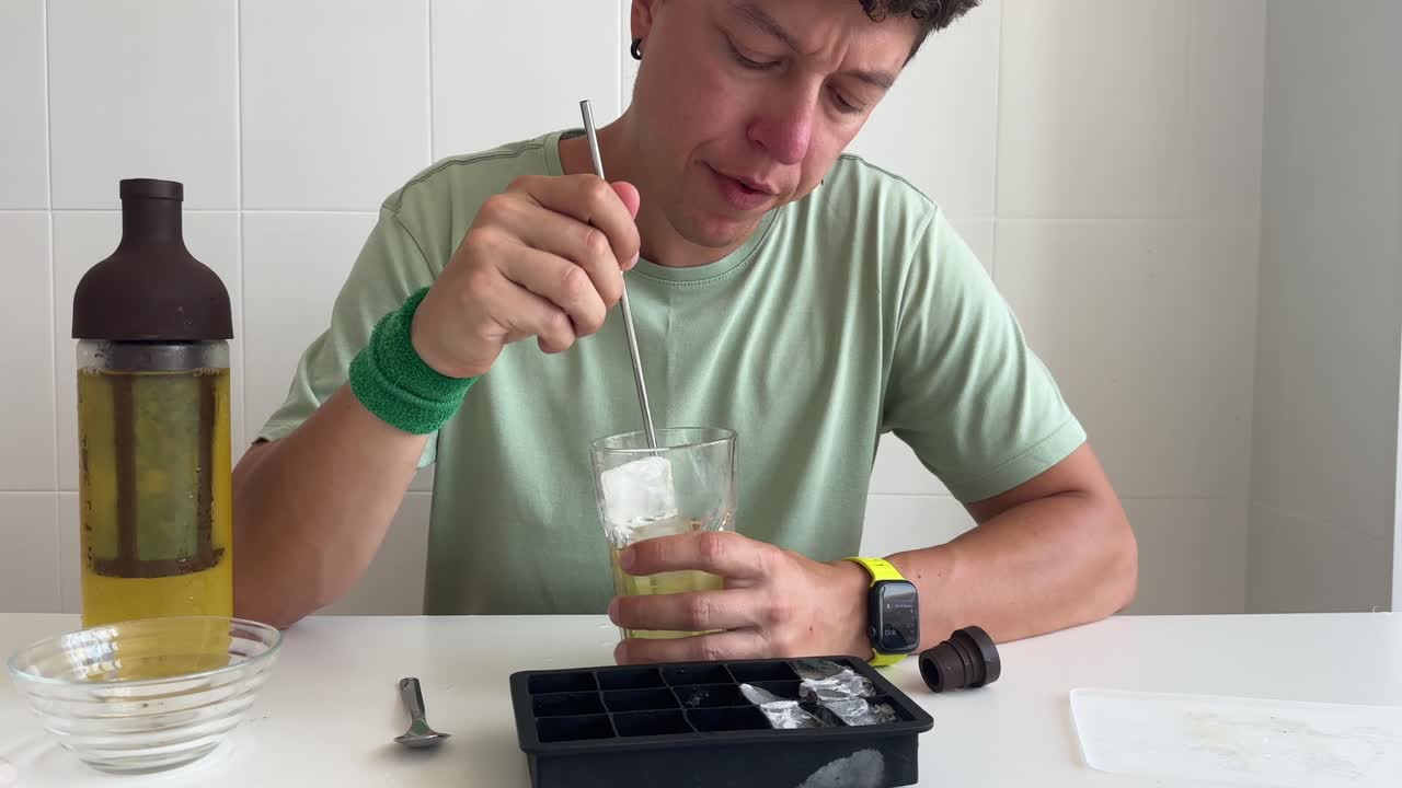 Hombre removiendo y bebiendo una bebida fría con hielo