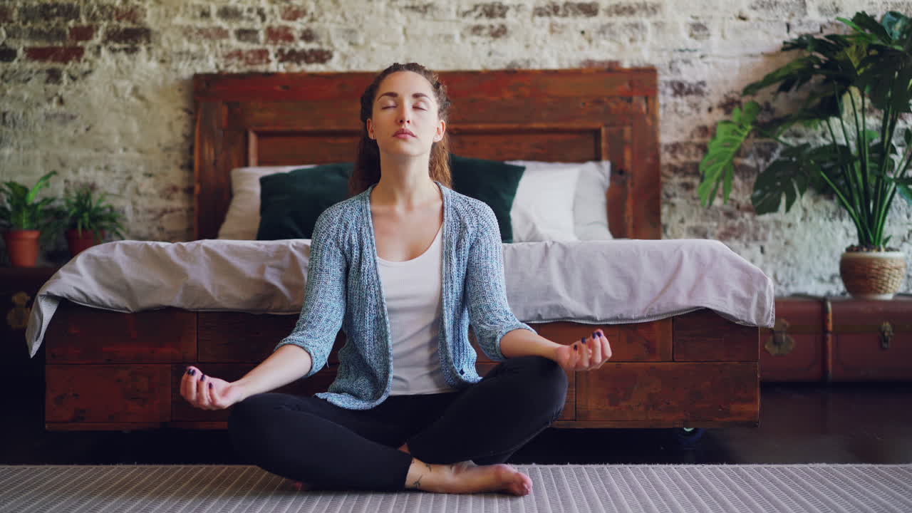 una mujer meditando en su dormitorio.