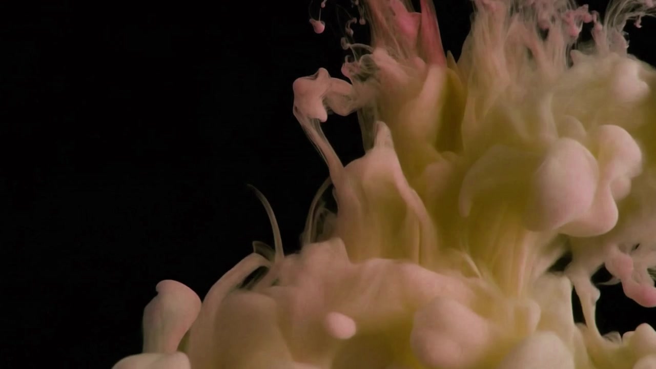 Gocce d'inchiostro rosa e giallo che turbinano nell'acqua