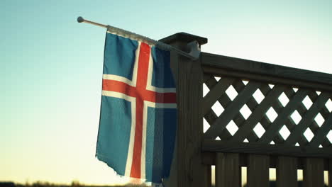 icelandic flag flapping in slow motion at dusk with mountains in the background