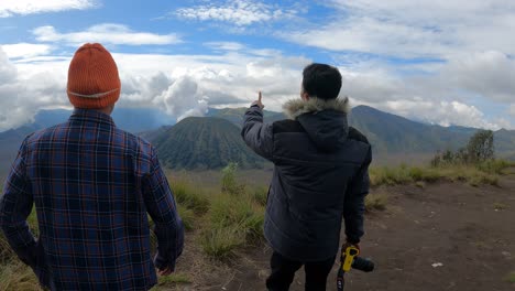 Dos-Turistas-Que-Caminan-Mientras-Señalan-El-Monte-Bromo,-Luego-Toman-Fotografías-De-La-Belleza-Del-Monte-Bromo