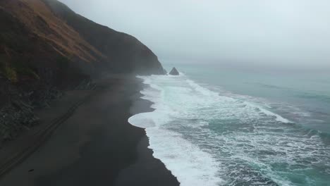 usal beach campground 4wd car truck tracks black sand mist rain fog lost coast trail aerial drone california pnw waves crashing early morning rugged coastline chimney rocks circle left motion