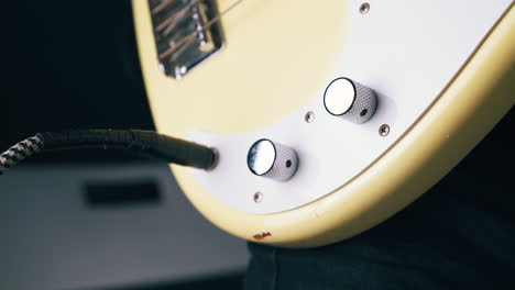 concentrated guitarist rotates volume and tone control knobs