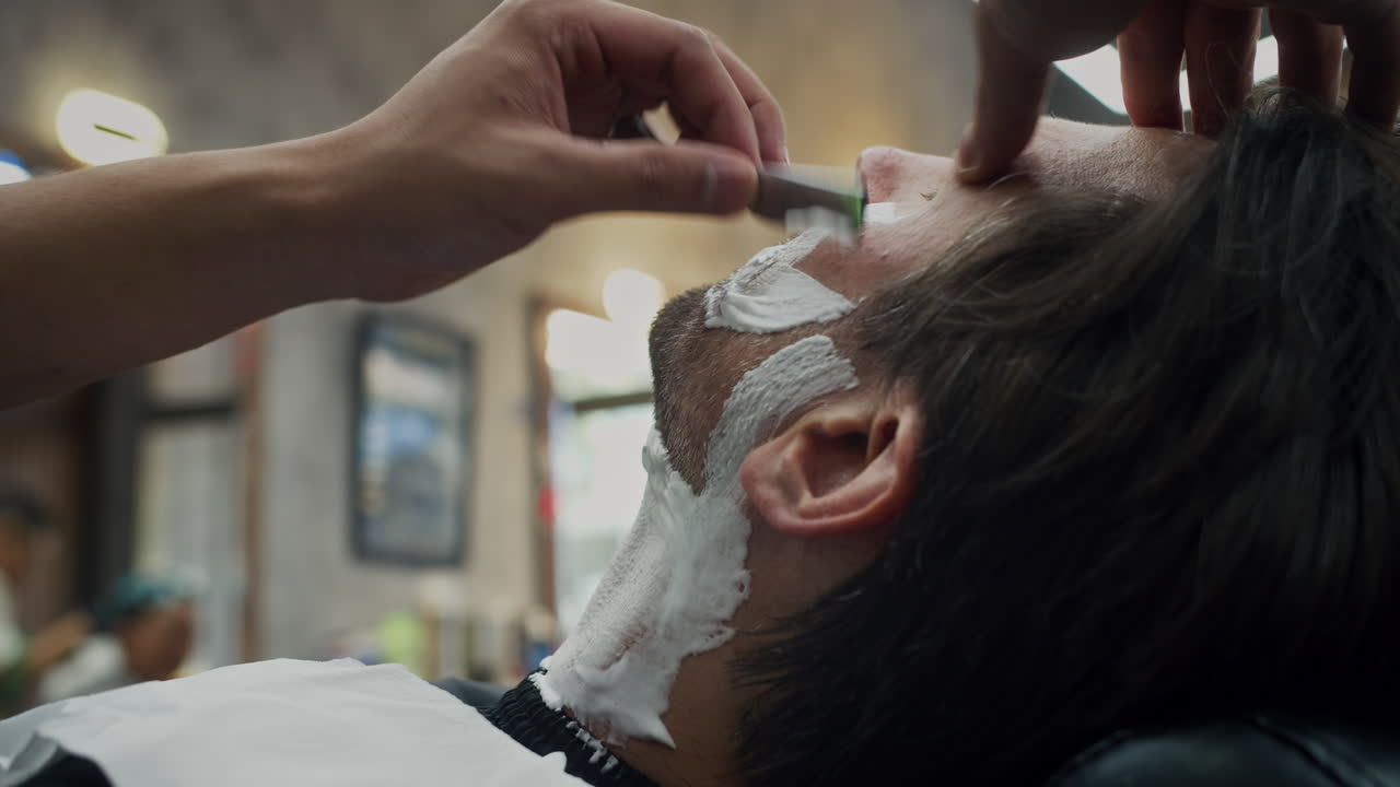 Un uomo si fa la barba in un negozio di barbiere