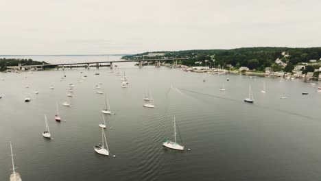 Aerial-expansive-view-of-coastal-town-with-sail-boats-and-vessels-over-bay-water-in-Rhode-Island