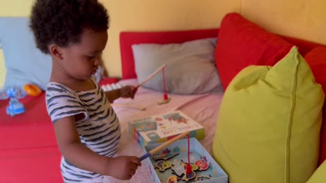 two year old cute afro european child enjoying with a fishing toy