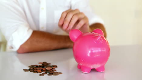 Businessman-putting-coins-into-piggy-bank