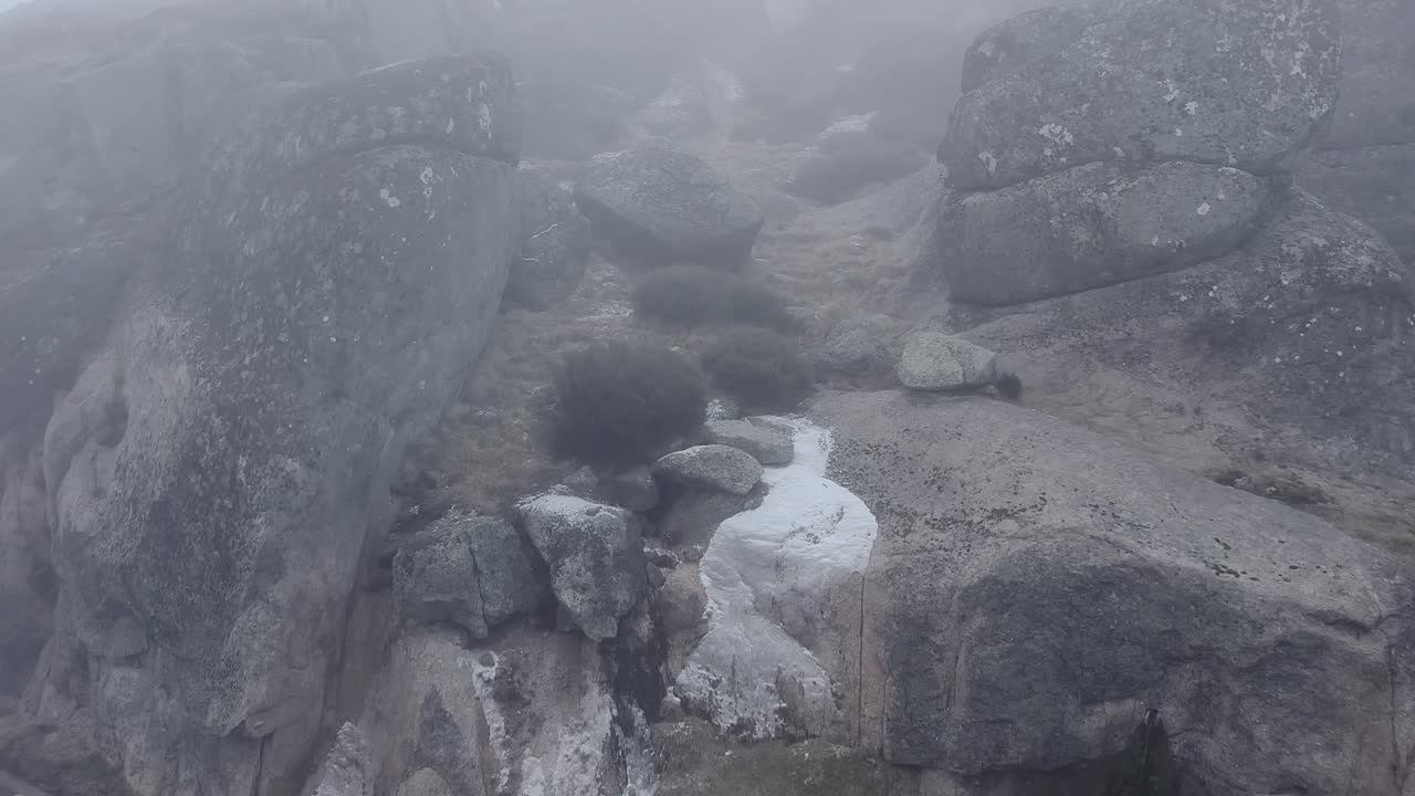 Serra da Estrela mountain road disappearing into thick fog, showing treacherous driving conditions and the challenging landscape of Portugal's highest range, drone push in shot