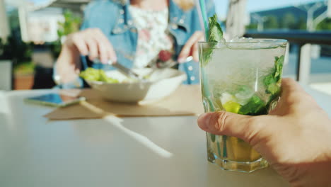 un couple se repose dans un café vue à la première personne - un homme tenant un verre avec un cocktail une femme en t