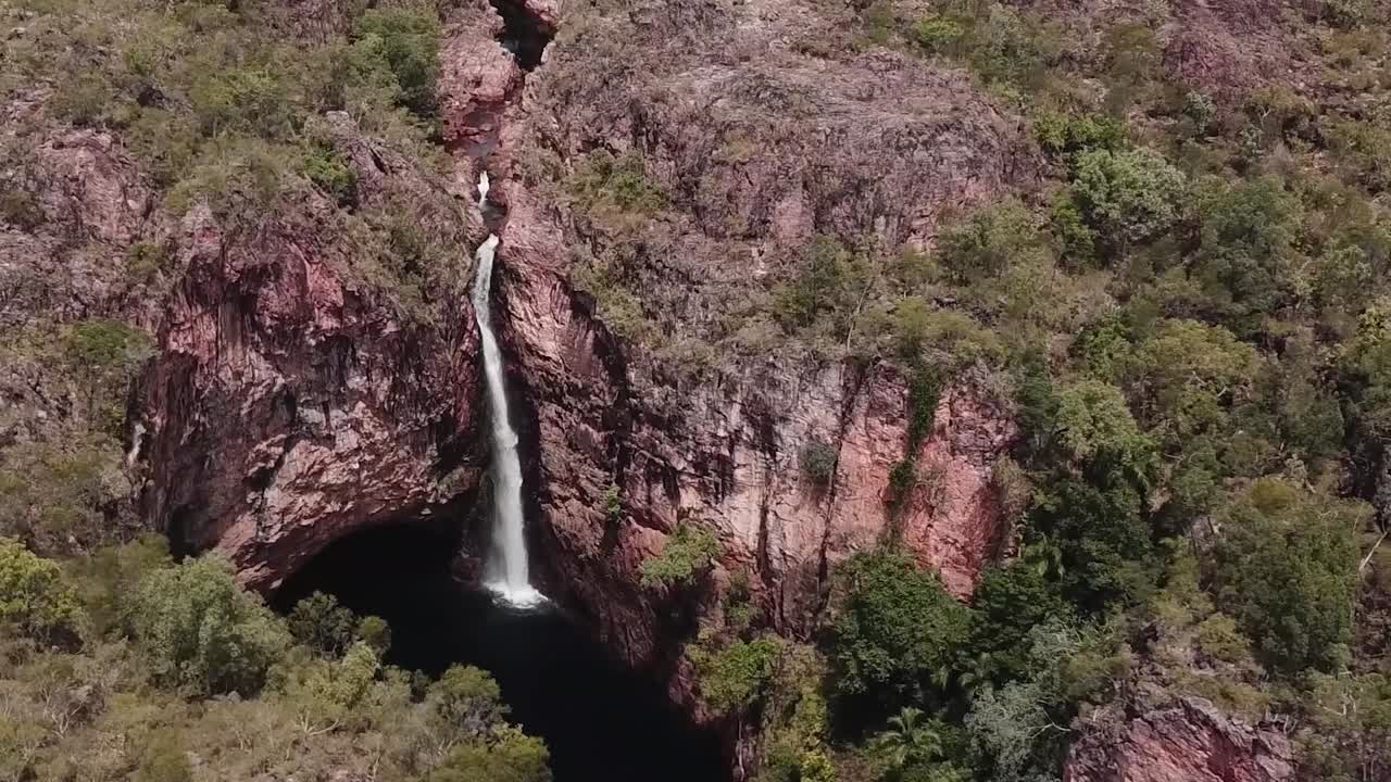 cascada alta que fluye desde el borde del acantilado entre el interior australiano
