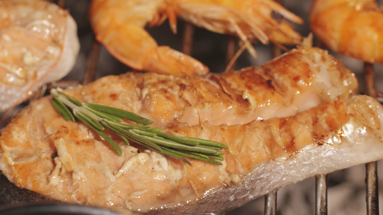 Chef cooking red salmon fish steaks with oil and spices on grill close-up. Prawns on fire throwing them on pan. Making Dorado fishes on frying grill. Restaurant Food concept. Sea food barbecue.