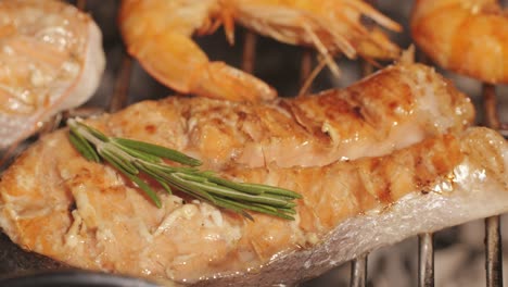 koch kocht rote lachsfischsteaks mit öl und gewürzen auf dem grill in nahaufnahme. garnelen auf dem feuer, die man auf die pfanne wirft. dorado-fische auf dem bratgrill machen. restaurant-food-konzept. seefood-barbecue.