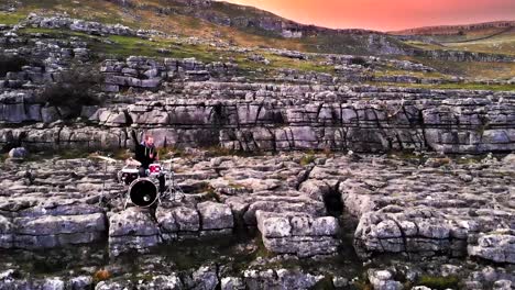 drummer playing solo on the cliff rocks at sunset, malham cove england