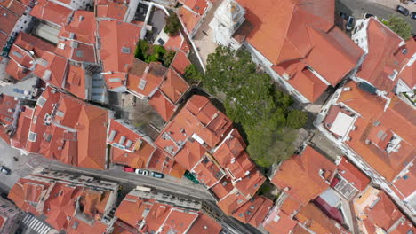 Aerial-overhead-top-down-view-of-orange-rooftops-and-streets-between-small-colorful-houses-in-dense-urban-city-center-of-Lisbon,-Portugal