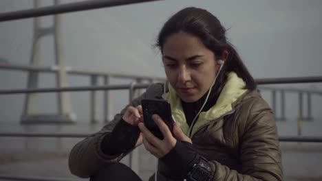 attractive young brunette lady with earphones using smartphone