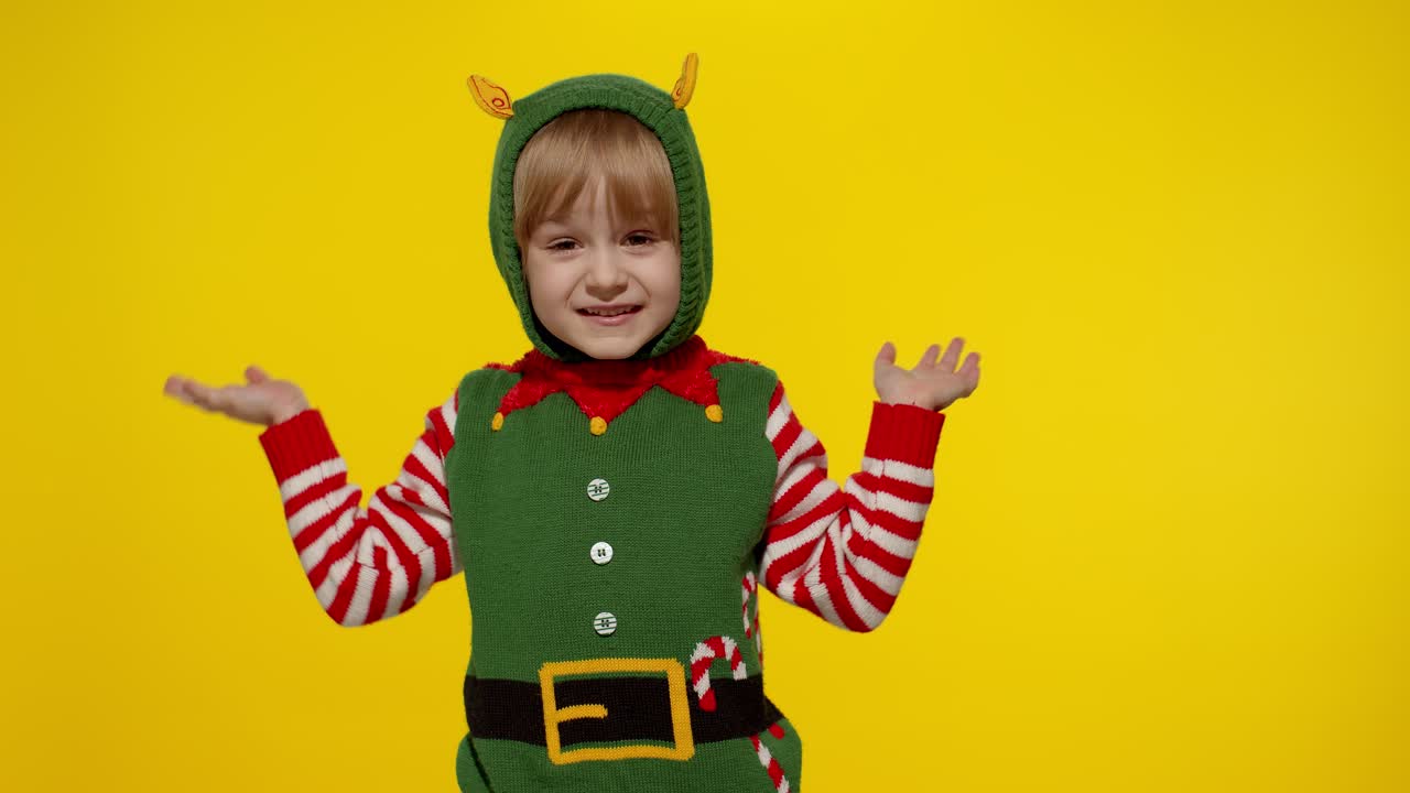 niña conmocionada con el disfraz de ayudante de santa elf de navidad. niño mira a la cámara y pregunta qué