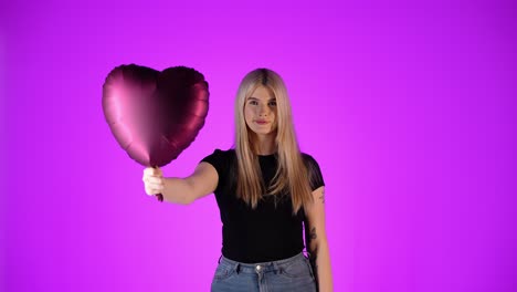 concept valentine's day, young woman holds red heart balloon heart at the camera