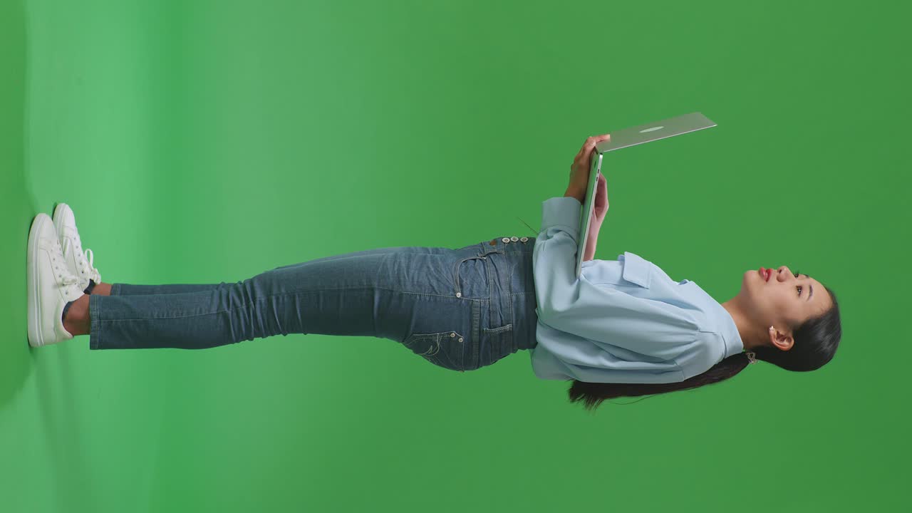 녹색 화면에서 노트북으로 일하는 여성