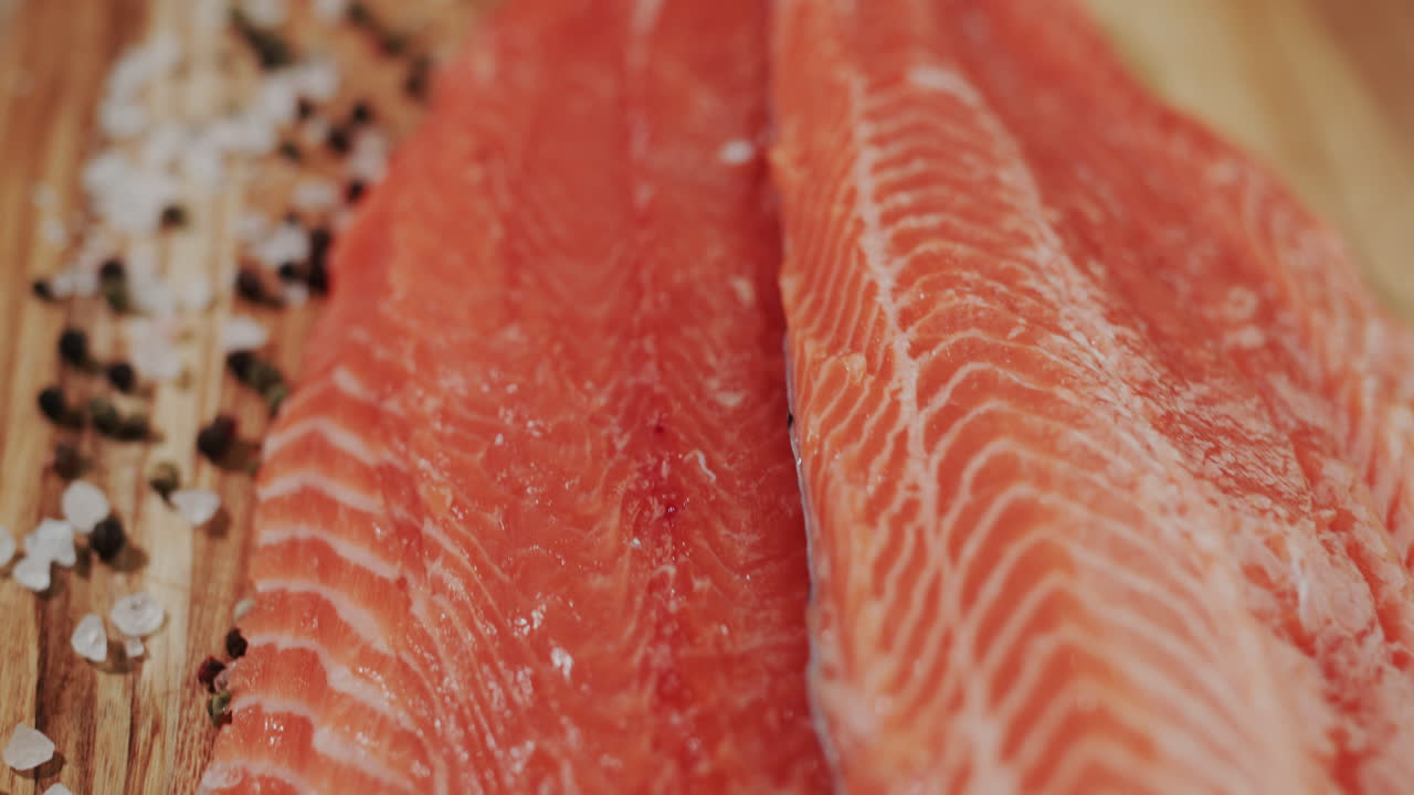filete de salmón en la mesa junto a la pimienta y la sal