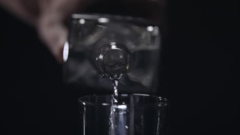 close up shot of pouring clear liquid from liquor bottle