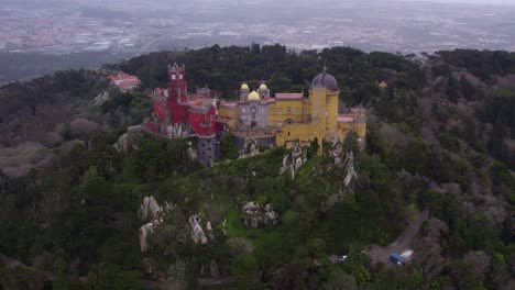 reveal shot of medieval castle palácio da pena portugal on cloudy day, aerial