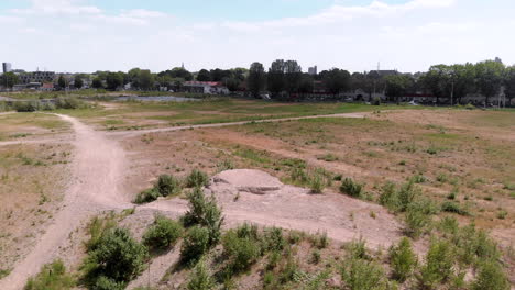 drone shot of a undeveloped vacant lot on the edge of a dutch city, with a skyline in the background