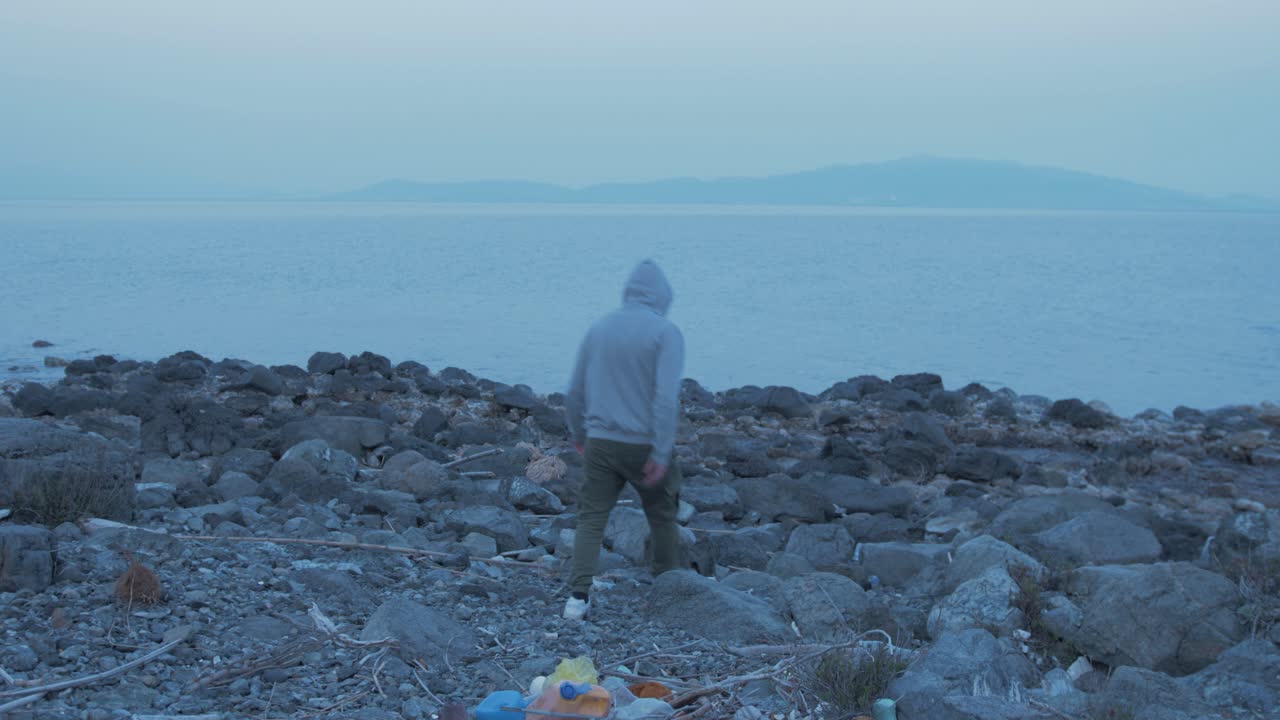 Giovane uomo getta plastica dalla tasca sulla riva del mare.