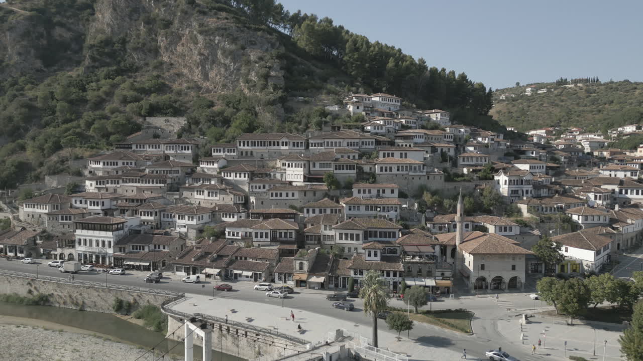 drone shot de la ciudad de berat y su castillo y fortaleza en albania, la ciudad de mil ventanas en un día soleado en el valle con cielo azul con casas blancas cerca de las montañas registro