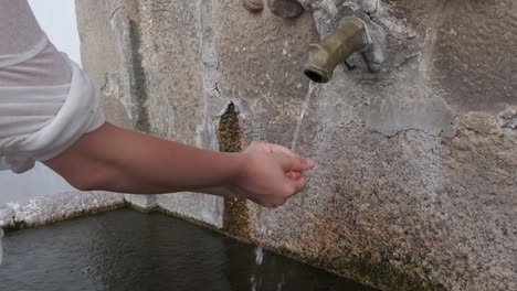 unrecognizable woman washes hands in fountain of monsanto village