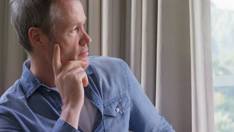 Man-sitting-on-the-chair-and-looking-through-the-window-4k