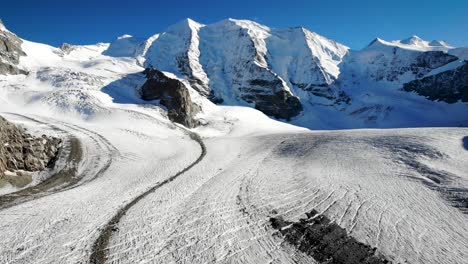 aerial flyover over pers glacier near diavolezza in engadin switzerland with a pan down from the piz bernina peak down to the crevasses